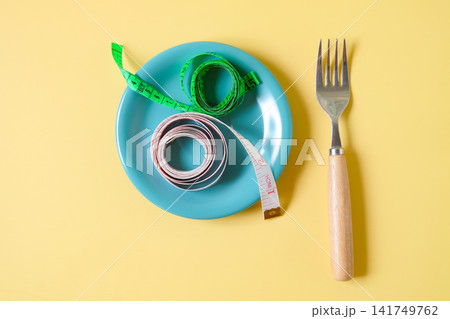 Measuring tape on dish with fork,Diet concept. Measuring tape on dish with fork,Diet concept. 141749762