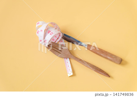 A white measuring tape rap around fork and knife ,Health care. A white measuring tape rap around fork and knife ,Health care. 141749836