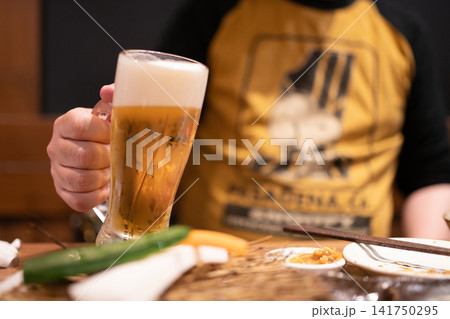 居酒屋で冷えた生ビールを持つ男性の手元 居酒屋で冷えた生ビールを持つ男性の手元 141750295