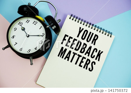 Your Feedback Matters text written on notepad with alarm clock flat lay on multicolor pastel background 141750372