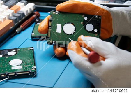 A technician about to repair a hard drive, a computer component. A technician about to repair a hard drive, a computer component. 141750691