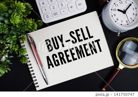 Buy-Sell Agreement text written on notepad with alarm clock, magnifying glass and calculator on black background Buy-Sell Agreement text written on notepad with alarm clock, magnifying glass and calculator on black background 141750747