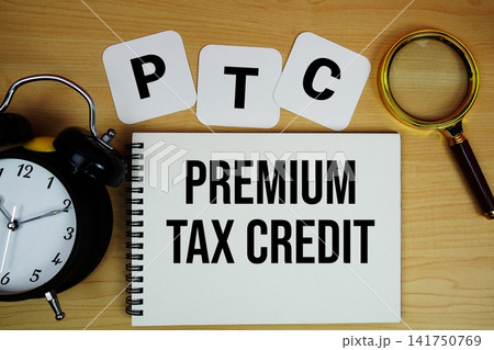 PTC Premium Tax Credit text written on notepad with magnifying glass and alarm clock on wooden background PTC Premium Tax Credit text written on notepad with magnifying glass and alarm clock on wooden background 141750769