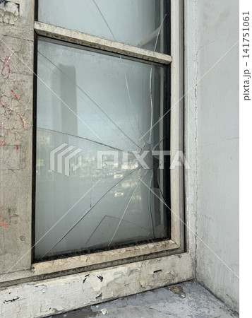 Broken window glass with visible cracks in an industrial setting illustrating urban decay Broken window glass with visible cracks in an industrial setting illustrating urban decay 141751061