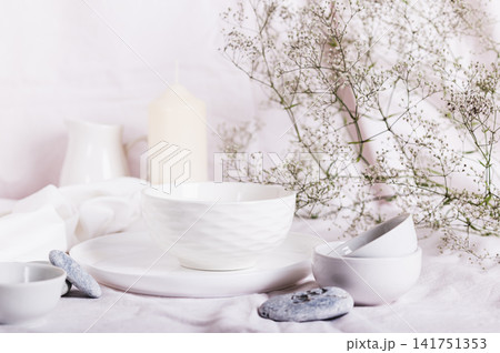 White ceramic dishes, white linen cloth, fabrics and dried flowers on the table 141751353