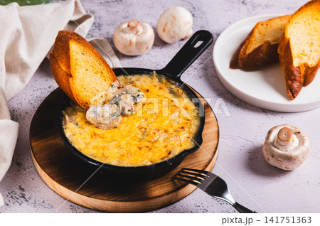 Mushroom julienne with cream and cheese crust in a frying pan on the table 141751363