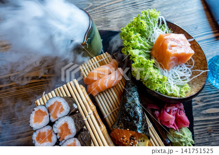 Artfully plated sushi assortment with smoked dry ice effect, fresh salmon, and elegant Japanese dining presentation Artfully plated sushi assortment with smoked dry ice effect, fresh salmon, and elegant Japanese dining presentation 141751525