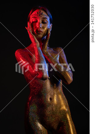 Glitter body art woman with red and gold lighting 141752030