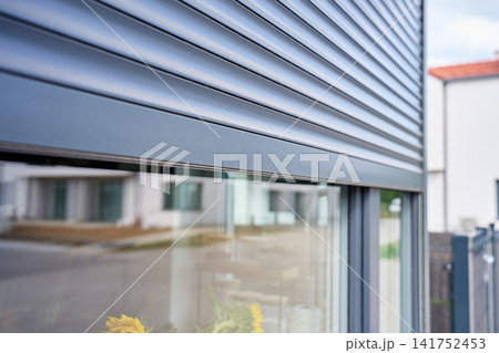 Exterior roller shutter is lowered over the upper part of modern residential window Exterior roller shutter is lowered over the upper part of modern residential window 141752453