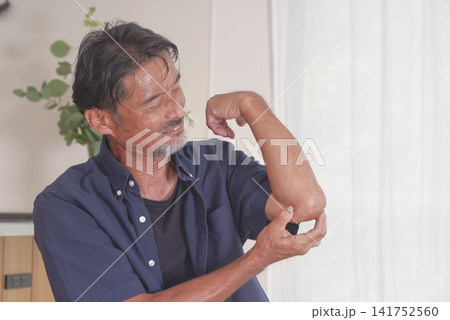 肘の痛みに顔をしかめる中高年男性 肘の痛みに顔をしかめる中高年男性 141752560