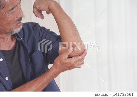 肘の痛みに顔をしかめる中高年男性 肘の痛みに顔をしかめる中高年男性 141752561