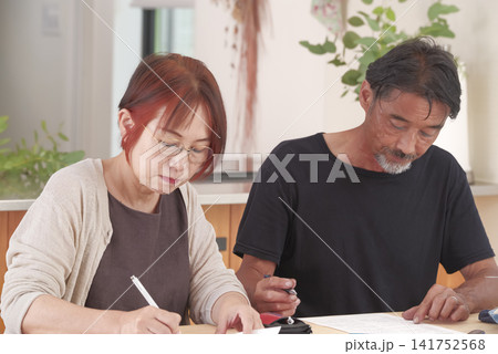 自宅で書類を記入する中高年夫婦 自宅で書類を記入する中高年夫婦 141752568
