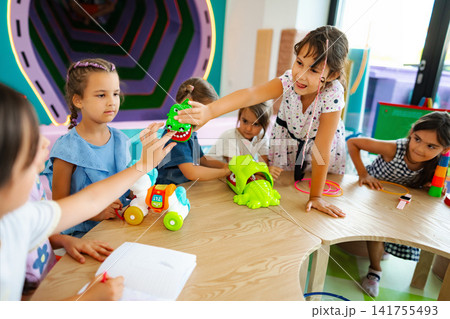 Children playing with toys at preschool table enjoying creative activity Children playing with toys at preschool table enjoying creative activity 141755493