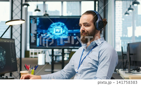 Programmer testing generative AI machine learning algorithms and listening music at work. IT expert wearing headphones scaling productivity with AI large language model written code, camera A Programmer testing generative AI machine learning algorithms and listening music at work. IT expert wearing headphones scaling productivity with AI large language model written code, camera A 141758383