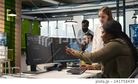 Manager teaching young technician how to develop software and optimize code using AI. Team leader guiding intern in office on how to use artificial intelligence to resolve bottlenecks, camera A Manager teaching young technician how to develop software and optimize code using AI. Team leader guiding intern in office on how to use artificial intelligence to resolve bottlenecks, camera A 141758439