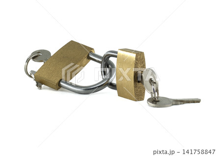 Two brass padlocks chained together with keys inserted, symbolizing security 141758847