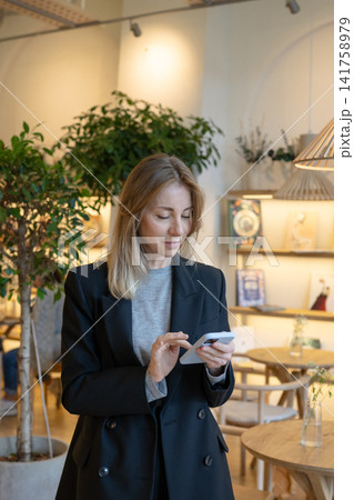 Positive successful business woman restaurant manager texting on smartphone during work break. Positive successful business woman restaurant manager texting on smartphone during work break. 141758979