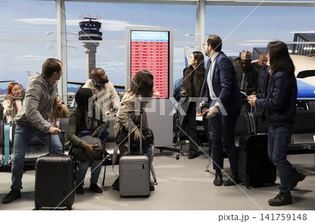 Worried about disruption, delayed flight and passengers in airport reacting to red alert on airline screen. Receiving bad news, flight cancellation and international travelers expressing anxiety Worried about disruption, delayed flight and passengers in airport reacting to red alert on airline screen. Receiving bad news, flight cancellation and international travelers expressing anxiety 141759148