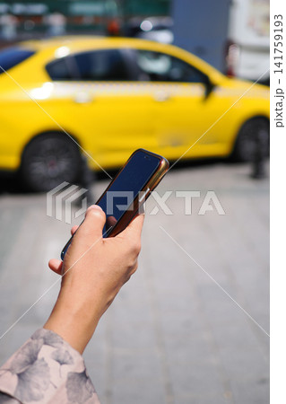 Person holding phone near yellow taxi in city Person holding phone near yellow taxi in city 141759193