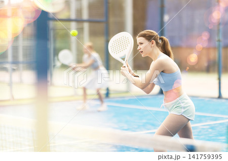 Woman with racket on court playing paddle in the background of sunshine Woman with racket on court playing paddle in the background of sunshine 141759395