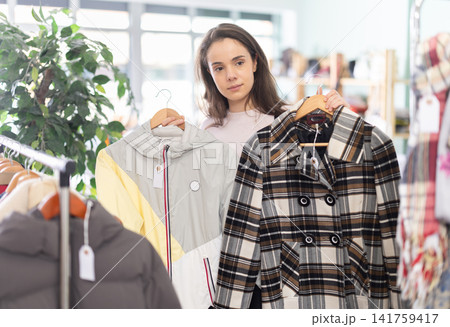 Young woman scans qr code of coat and jacket in store Young woman scans qr code of coat and jacket in store 141759417
