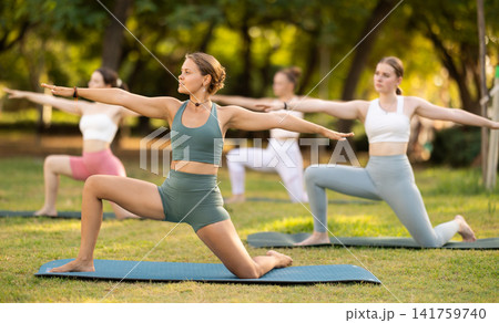 Group yoga classes in summer park - girls in different yoga poses 141759740