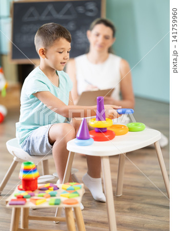 Child psychologist asks boy to play game: using both hands to simultaneously navigate maze drawn on board Child psychologist asks boy to play game: using both hands to simultaneously navigate maze drawn on board 141759960
