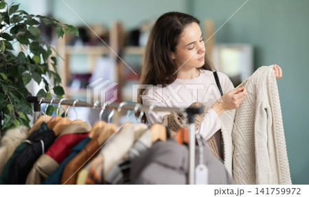 Girl client pick up and choose clothes, is busy sweater 141759972