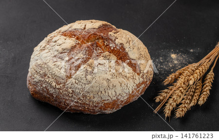 Artisan sourdough bread loaf with wheat ears on dark background Artisan sourdough bread loaf with wheat ears on dark background 141761223