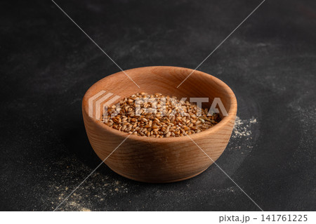 Wheat grains in wooden bowl on dark background with copy space 141761225