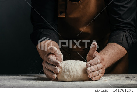 Baker shaping artisan bread dough by hand on floured table Baker shaping artisan bread dough by hand on floured table 141761276