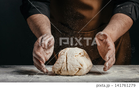 Baker shaping bread dough with flour dust on worktable Baker shaping bread dough with flour dust on worktable 141761279