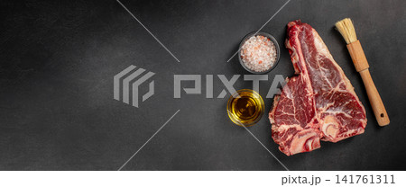 Raw tomahawk steak with salt and oil on dark background 141761311