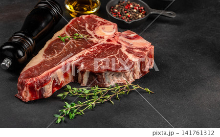 Raw t bone beef steak with herbs and spices on dark background Raw t bone beef steak with herbs and spices on dark background 141761312