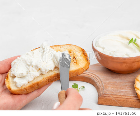 Spreading cream cheese on toasted bread with butter knife 141761350
