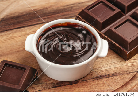 Dark Chocolate Ganache in White Bowl with Chocolate Bars Close Up Dark Chocolate Ganache in White Bowl with Chocolate Bars Close Up 141761374