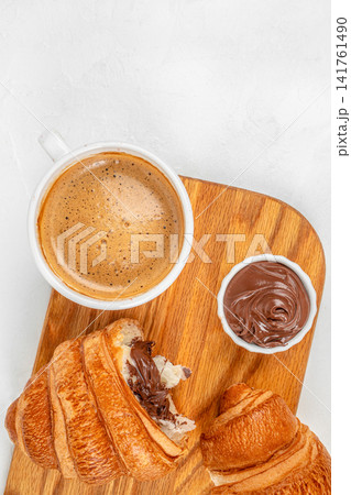 Coffee with chocolate croissants and chocolate spread on wooden board top view Coffee with chocolate croissants and chocolate spread on wooden board top view 141761490