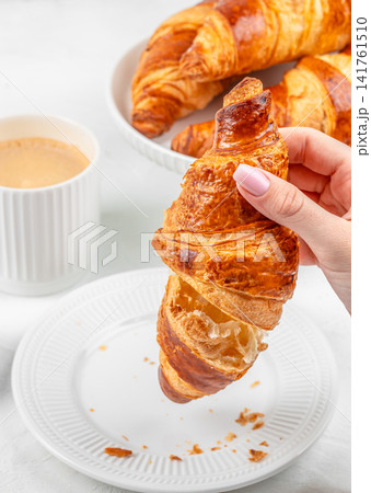 Woman Holding Fresh Croissant with Coffee and Pastries for Breakfast 141761510