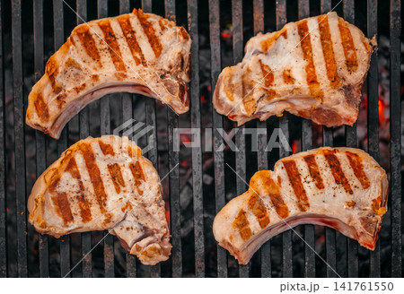 Grilled pork chops on barbecue grill with charcoal top view 141761550