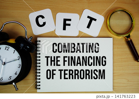 CFT Combating the Financing of Terrorism text written on notepad with magnifying glass and alarm clock on wooden background 141763223