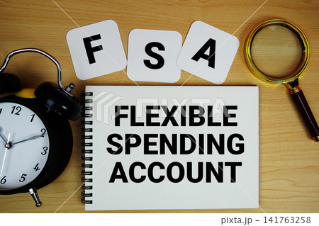 FSA Flexible Spending Account text written on notepad with magnifying glass and alarm clock on wooden background FSA Flexible Spending Account text written on notepad with magnifying glass and alarm clock on wooden background 141763258