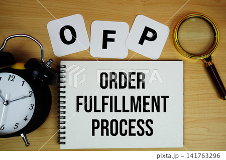 OFP Order Fulfillment Process text written on notepad with magnifying glass and alarm clock on wooden background 141763296