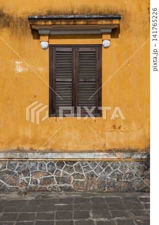 Traditional yellow building wall with wooden window shutters in Hoi An Ancient Town, Vietnam Traditional yellow building wall with wooden window shutters in Hoi An Ancient Town, Vietnam 141765226