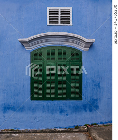 Green window shutters on a vibrant blue wall in Hoi An Ancient Town, Vietnam 141765230
