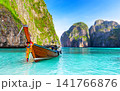 Traditional Thai longtail boat floating in the turquoise waters of Maya Bay on Phi Phi Islands, Thailand. One of the most iconic tropical travel destinations in Southeast Asia. 141766876
