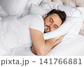 Young adult man sleeping comfortably, while resting on a soft pillow. Concept of healthy sleep, relaxation, wellness, recovery and everyday comfort. 141766881