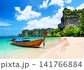 Traditional longtail boat resting on the white sand of Railay Beach near Ao Nang, Thailand. Tropical scenery with turquoise water and dramatic limestone cliffs. 141766884