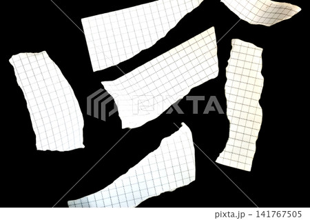 Scraps of checkered paper scattered on a black background. Scraps of checkered paper scattered on a black background. 141767505