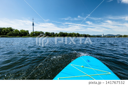 First person view from a stand up paddleboard on a river with sailboats in background, illustrating summer water sport. 141767532
