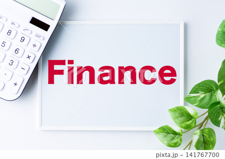 Finance(ファイナンス)の文字のホワイトボードと白い電卓 Finance(ファイナンス)の文字のホワイトボードと白い電卓 141767700
